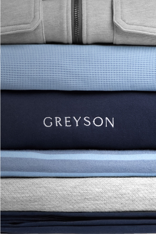 Stack of folded clothing with 'GREYSON' branding on a blue background