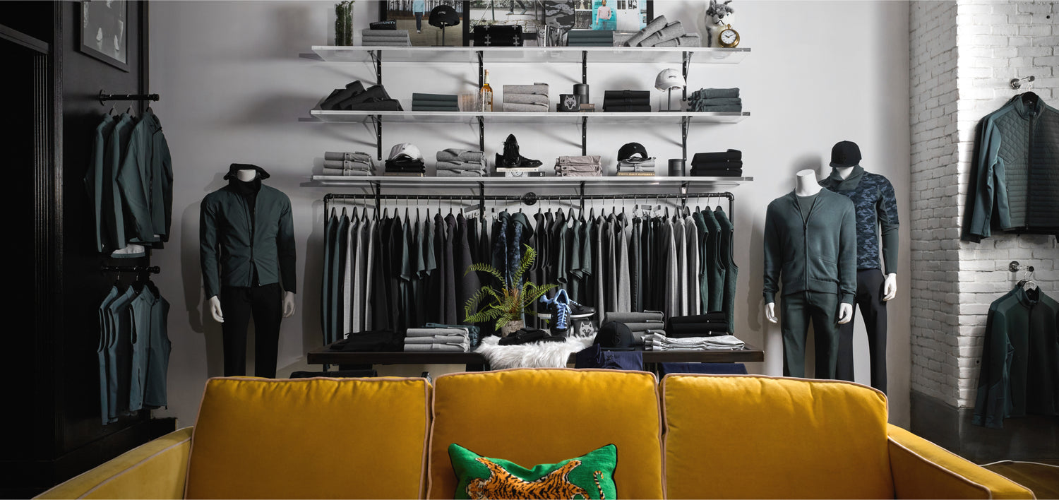 Clothing store interior with mannequins and shelves displaying various garments.