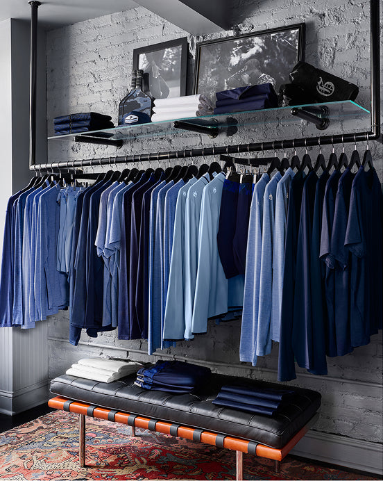 Various Greyson products displayed on a store rack with a bench featuring folded clothes on it