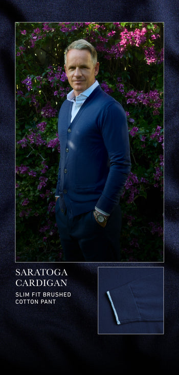 Man wearing a blue cardigan and dark pants standing in front of purple flowers, with text about clothing items.