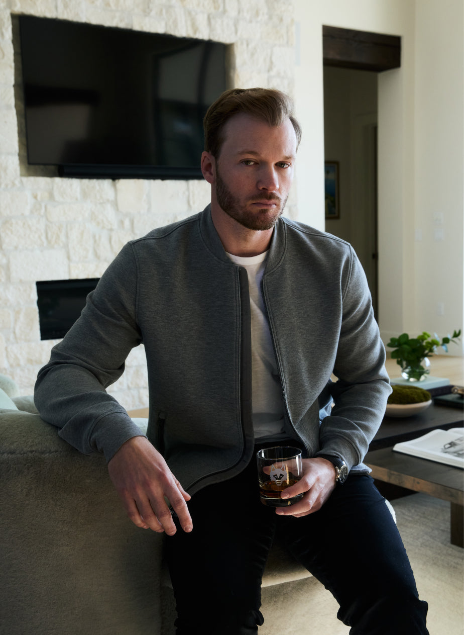 Man sitting on a couch in a modern living room holding a glass.