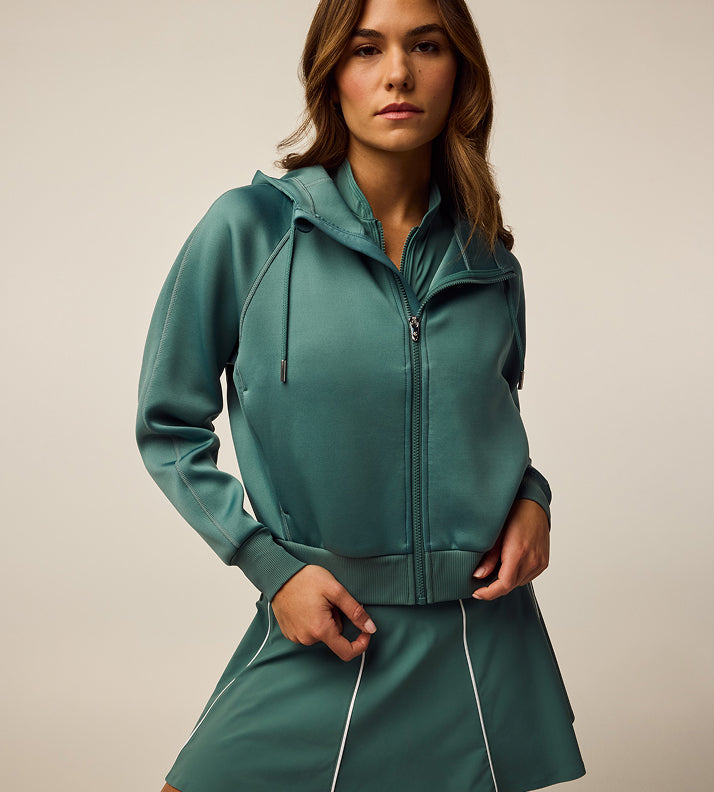 Woman wearing a teal tracksuit against a neutral background