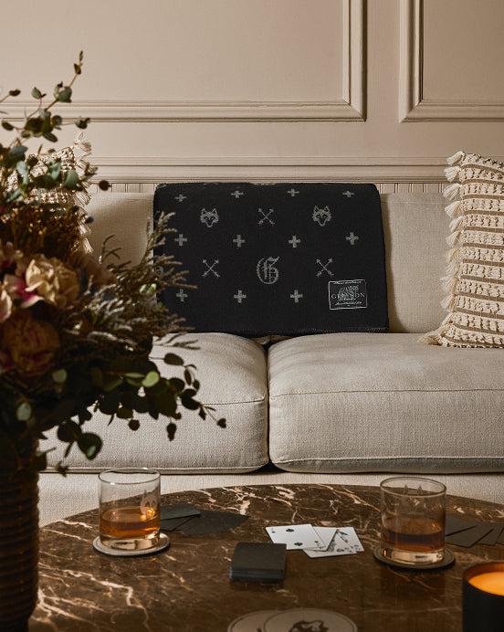 a beige couch with a greyson throw blanket behind a coffee table